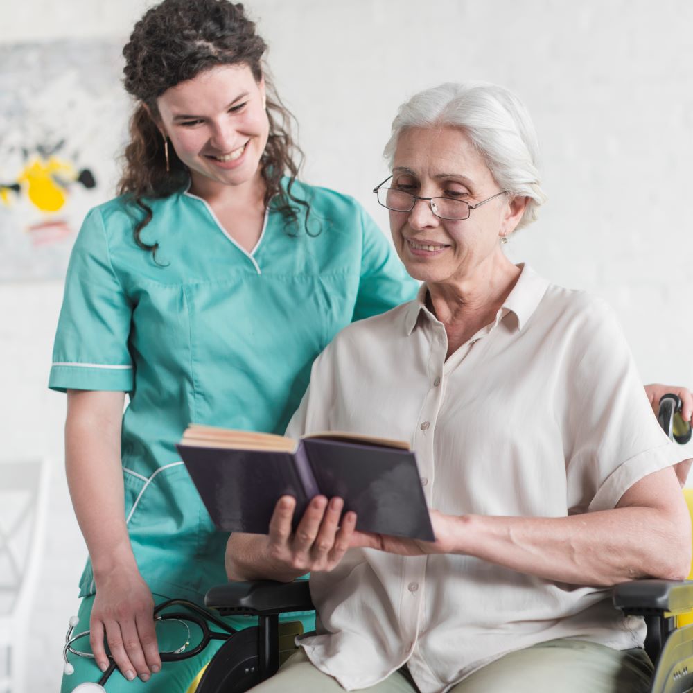 nurse standing disabled senior woman reading book